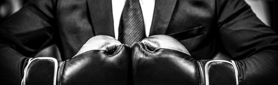 Businessman with boxing gloves is ready for corporate battle.