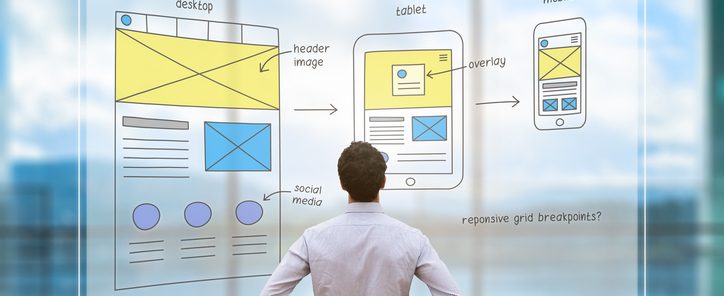 Website development UI/UX front end designer reviewing sketched wireframe layout design mockup for responsive web content with AR screen