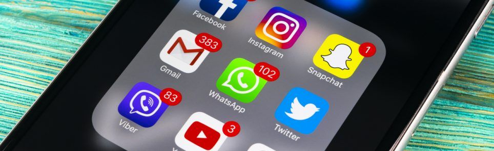 Smartphone with icons of social media on screen on wooden table. Smartphone life style smartphone. Starting social media app. Office shot