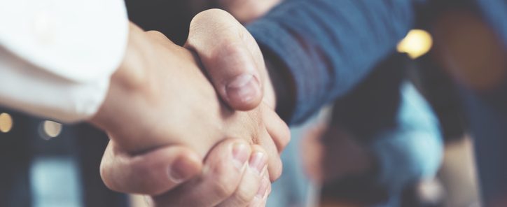 Business people shaking hands in the office after succesful meeting. Three persons