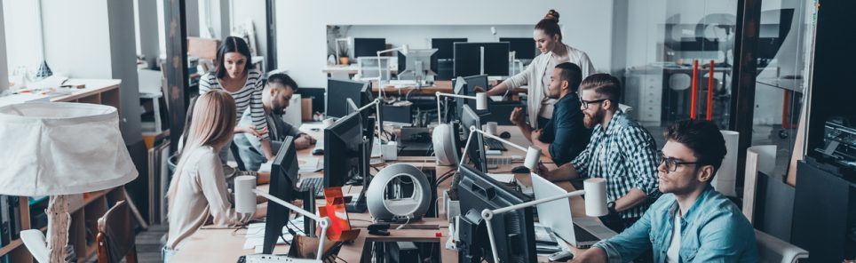 Group of young business people concentrating at their work while sitting at the large office desk together