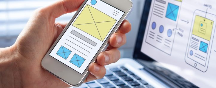 Mobile responsive website development with UI/UX front end designer previewing wireframe sketch layout design mockup on smartphone screen