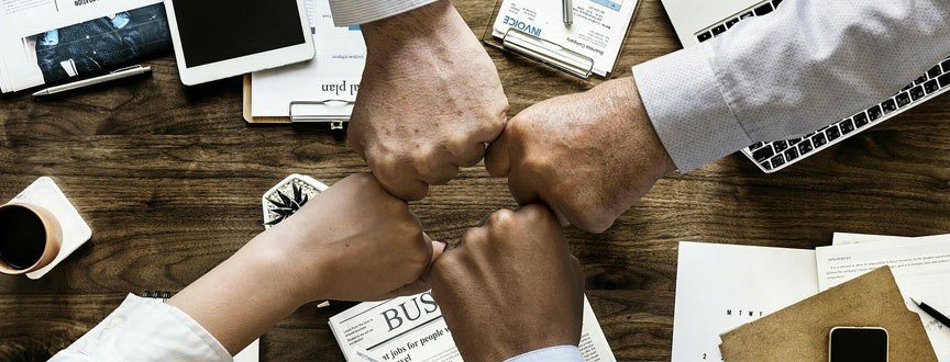 four people putting their hands in a circle