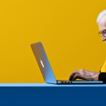 Older man typing on an Apple MacBook