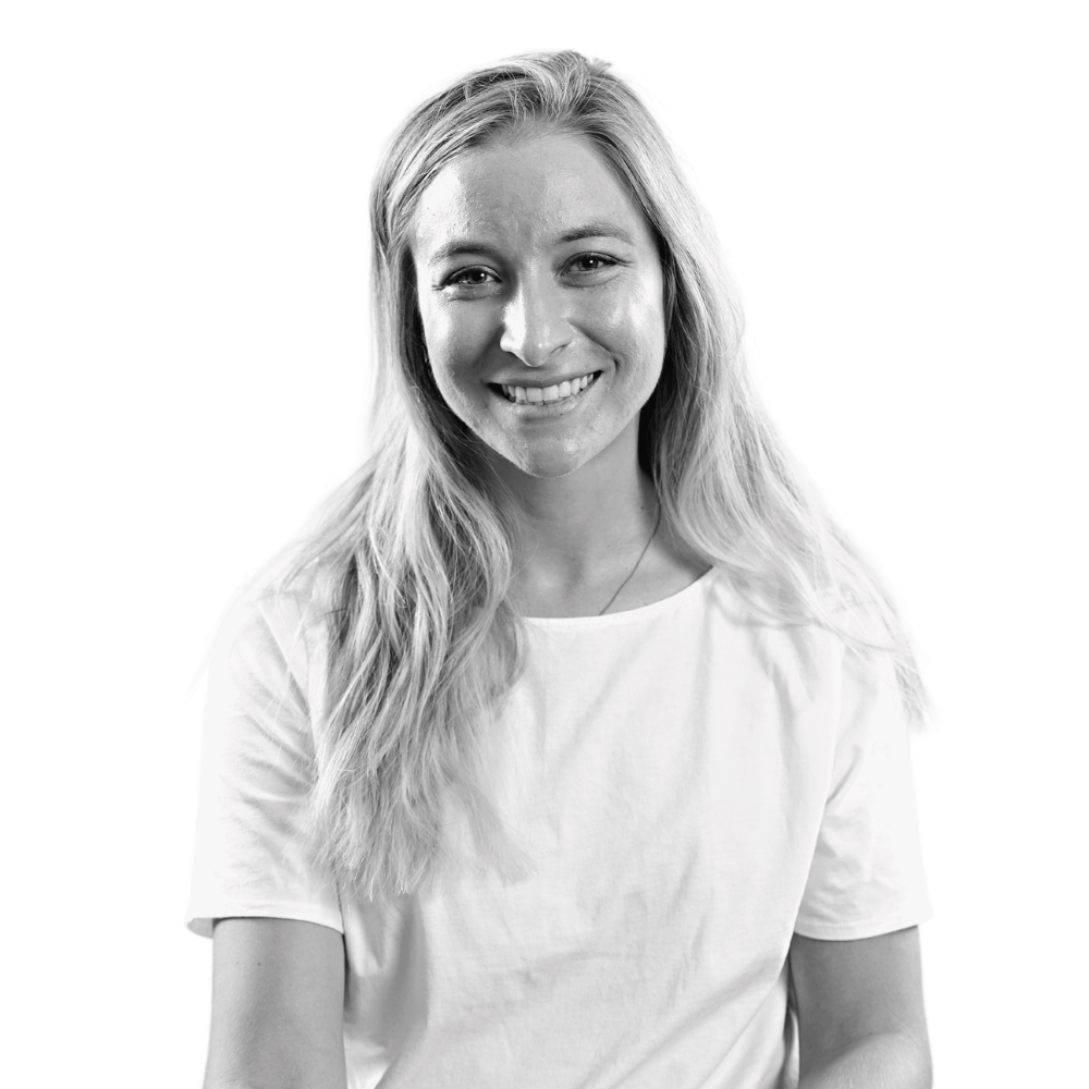 Black and white portrait of a smiling woman with long hair wearing a white t-shirt.