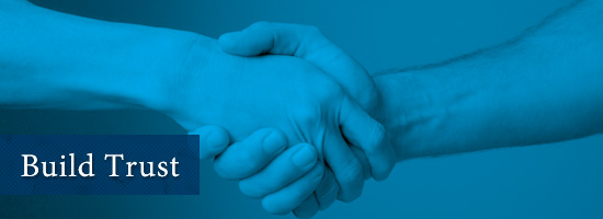 Two hands engaged in a handshake against a blue background with the words 'Build Trust' beside them.