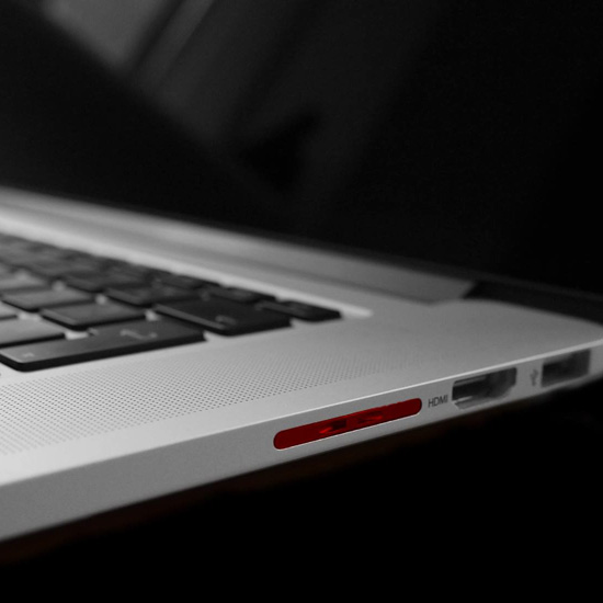 Close-up of a silver laptop's side edge with a red detail, USB port, HDMI port, and headphone jack visible.