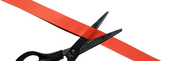 Black scissors cutting a diagonal red ribbon.