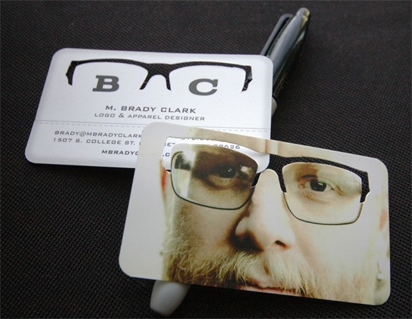 Two business cards for M. Brady Clark, a logo and apparel designer, with a creative design. The top card has a cut-out of glasses that align with the eyes on the photo of a man's face on the bottom card, creating an illusion of the glasses being worn.