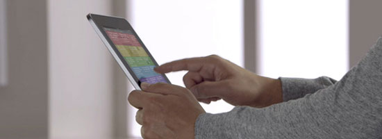 Person using a tablet with a colorful screen interface, holding it with one hand and touching the screen with the other.