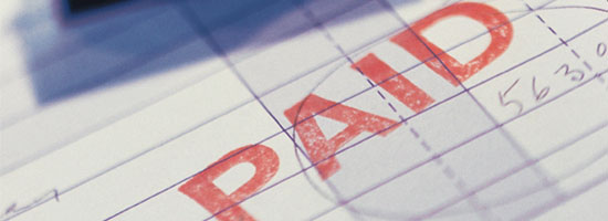 Close-up of a stamped 'PAID' in red on a lined invoice paper with handwritten numbers in blue ink.