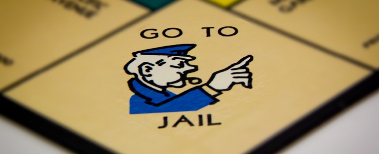 Close-up of the 'Go to Jail' space on a Monopoly board with an illustration of a police officer pointing.