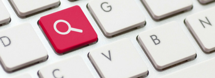 Close-up of a computer keyboard with a red search key featuring a white magnifying glass symbol among white standard keys.