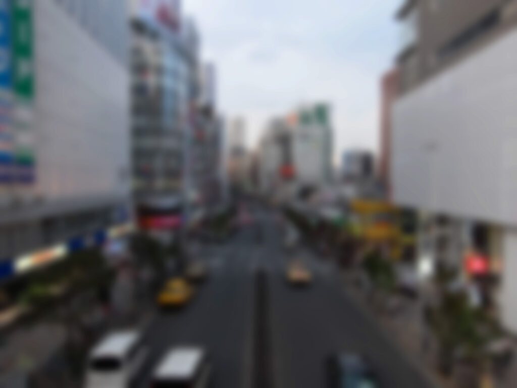 A blurred image of a busy urban street with indistinct vehicles and buildings.