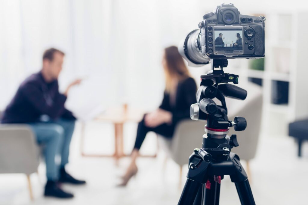 A camera records an interview between 2 people