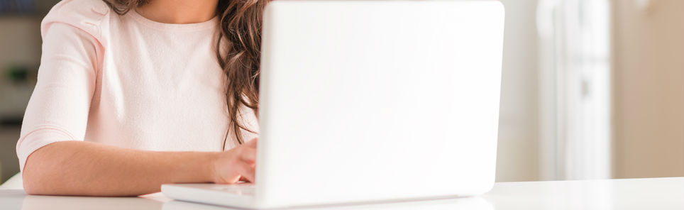 A person sitting in front of an open laptop, with only their torso and arms visible, typing on the keyboard.