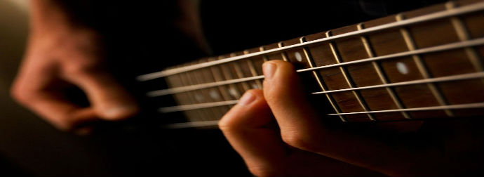 Close-up of a person's hand playing chords on a guitar fretboard.