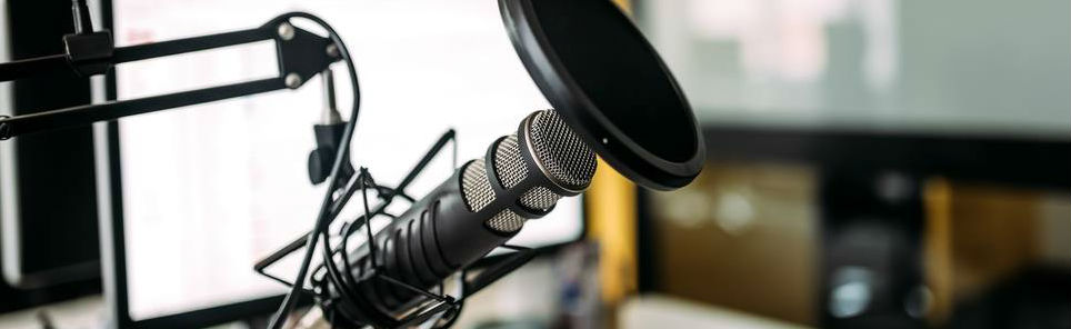 Professional microphone with boom arm, shock mount, and pop filter in a studio setting.