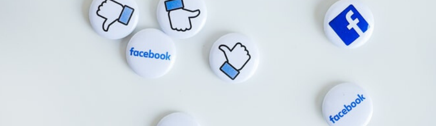 A collection of round pins with Facebook logos and thumbs-up and thumbs-down symbols on a white background.