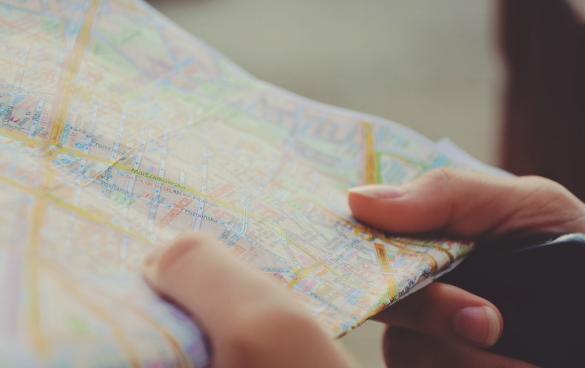 Hands holding a folded paper city map with colorful markings.