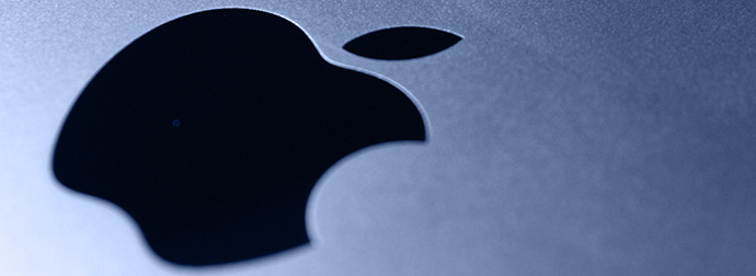 Close-up of the Apple Inc. logo on a brushed metallic surface with a gradient lighting effect.