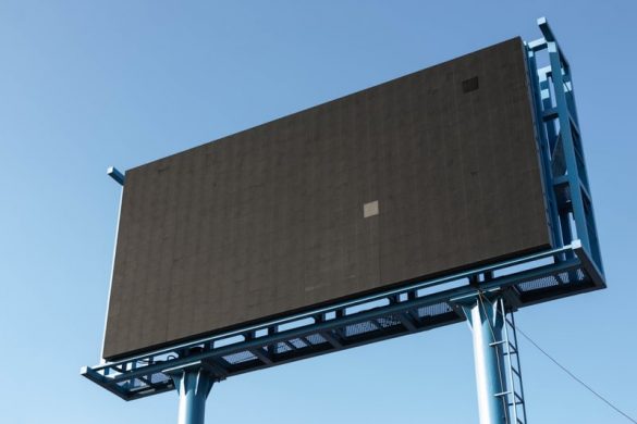 A large, blank digital billboard mounted on a metal frame against a clear blue sky.