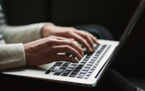 Close-up of a person's hands typing on a laptop keyboard.