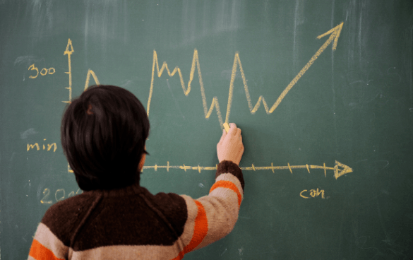 Person drawing an upward trending graph on a chalkboard, indicating data analysis or presentation.