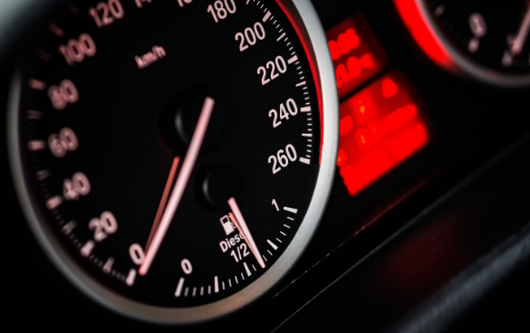 Close-up of a vehicle's speedometer with the needle just above 0 km/h, a digital display with a red warning, and a diesel fuel gauge indicating just over half full.