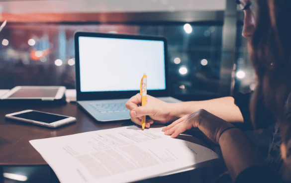 Woman writing on a notepad in front of a computer