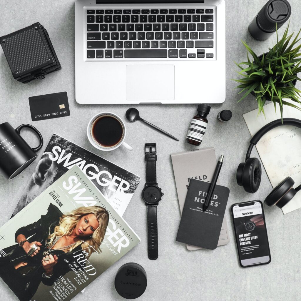 laptop, magazines, and other items laid out on table