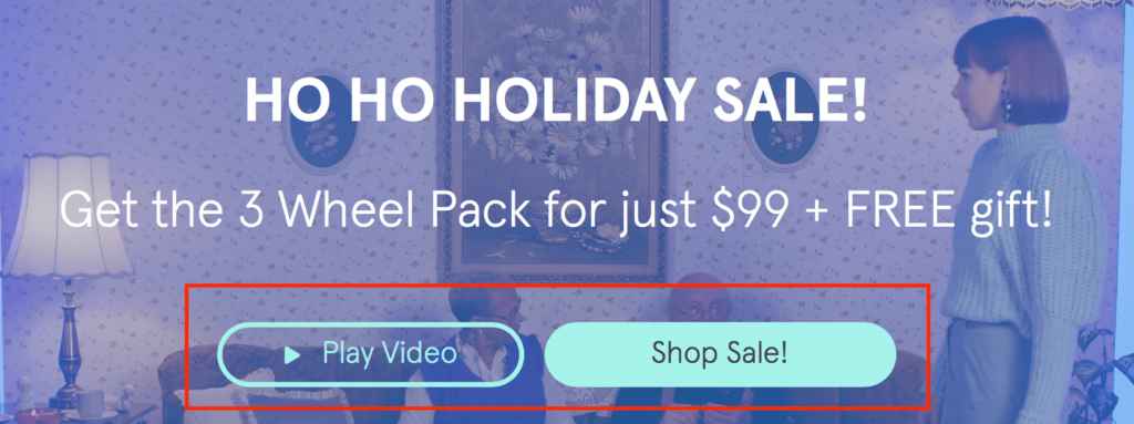 Holiday sale advertisement with a woman in a blue sweater, featuring an offer for a 3 Wheel Pack at $99 with a free gift, and call-to-action buttons to play a video and shop the sale.