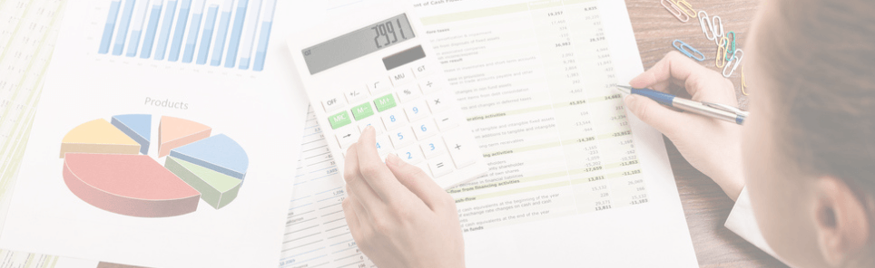 Person analyzing financial documents with a calculator and pen, with a pie chart and bar graph indicating sales or financial data.