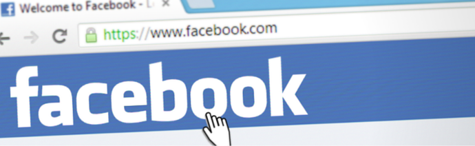 Close-up of a computer screen with the Facebook homepage, cursor pointing at the Facebook logo, and a secure URL in the address bar.