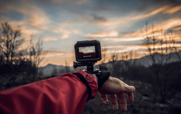 A person records footage of a sunset with a GoPro camera strapped to their wrist