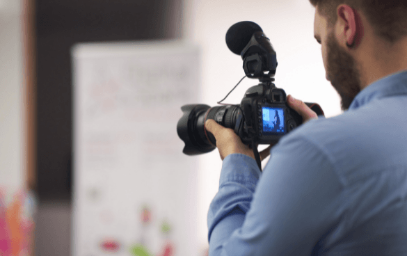 A man holds a video camera while recording an event