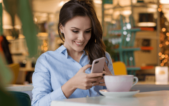 A woman smiles while looking at her smartphone