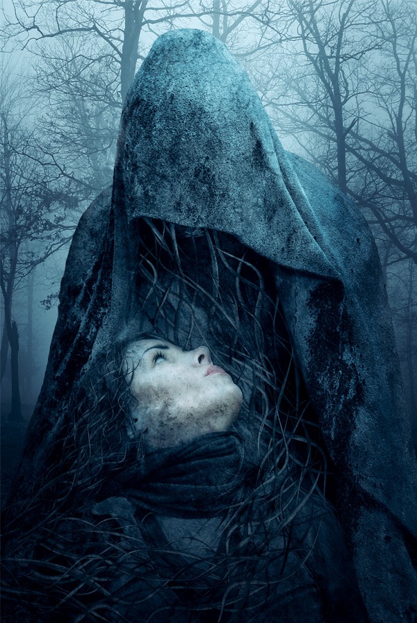 Surreal image of a hooded stone-like figure with a woman's face looking upwards from its hollowed chest, entwined with branches, set in a foggy forest.