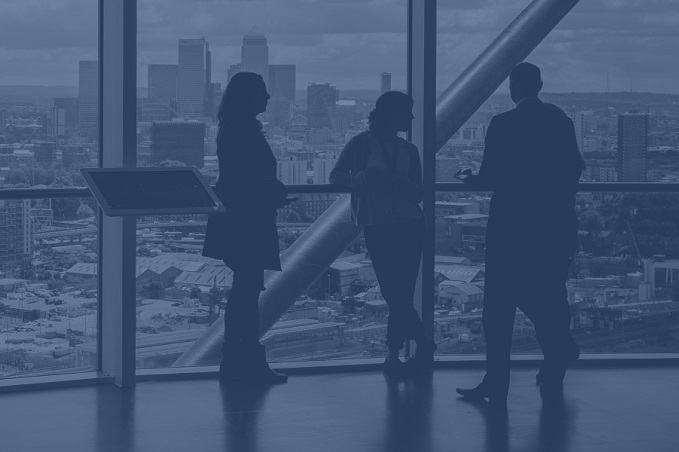 Silhouettes of three people conversing in front of a window overlooking a city skyline.