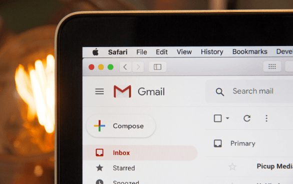 Close-up of a computer screen displaying an open Gmail inbox in the Safari web browser, with options like 'Compose', 'Inbox', and 'Starred' visible.