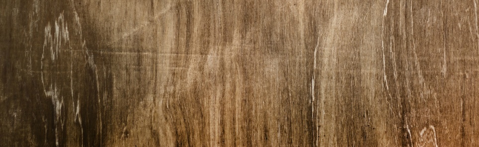 Close-up of a distressed wooden surface with visible grain patterns in warm brown tones.