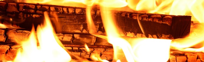 Close-up of a bright fire burning wood on a brick structure.