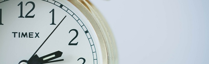 Close-up of a TIMEX wall clock showing approximately 10:09 with a white face, black numbers and hands, and a wooden frame.