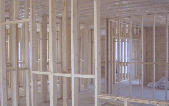 Interior view of a building under construction with wooden stud framing outlining future rooms and doorways.