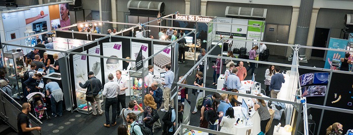 An indoor trade show with attendees visiting various exhibition booths, interacting with exhibitors, and networking in a busy hall.