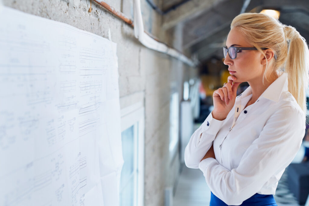 Thoughtful female architect looking on blueprint