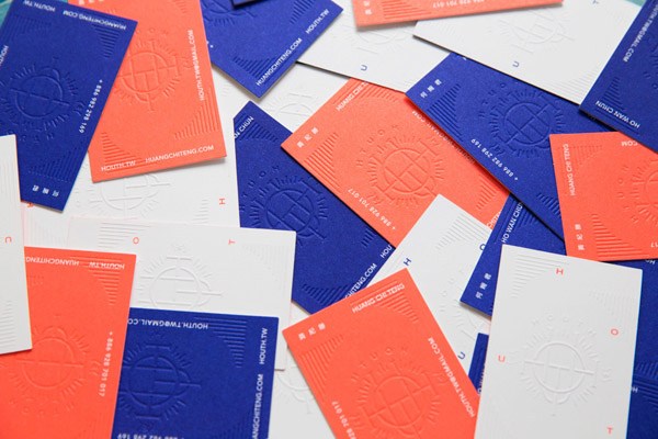 A variety of red and blue business cards with embossed designs scattered on a white surface.