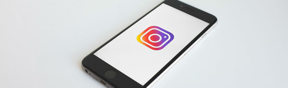 Smartphone lying on a white surface displaying the Instagram logo on its screen.