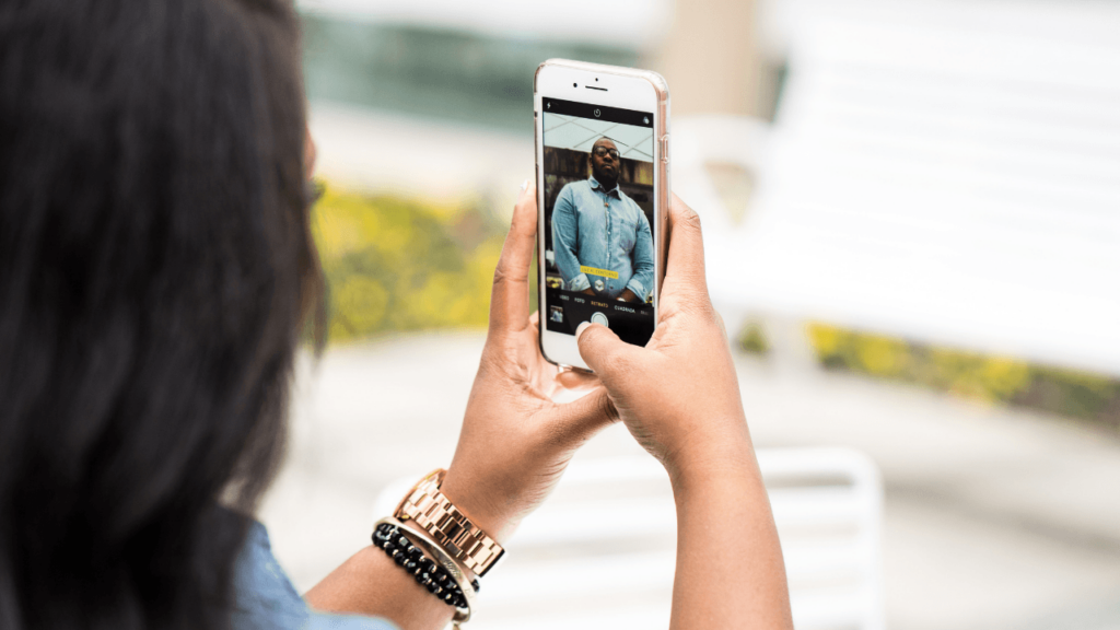 A person takes a photo of another person using a cell phone