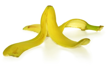 A peeled banana with its peel splayed out on a white background.